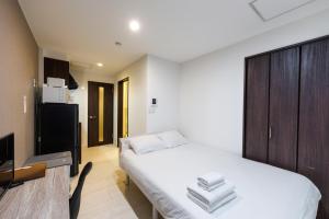 a bedroom with a white bed and a tv at Niseko Hirafu Ski Resort Condo in Kutchan