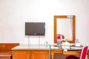 Habitación con escritorio y TV en la pared. en RedDoorz Plus near Brawijaya Museum, en Malang