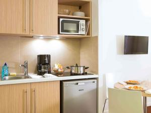 a kitchen with a stove and a microwave at Aparthotel Adagio Access Le Havre Les Docks in Le Havre
