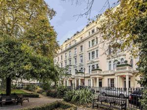 a large white building with benches in front of it at Mercure London Hyde Park Hotel in London