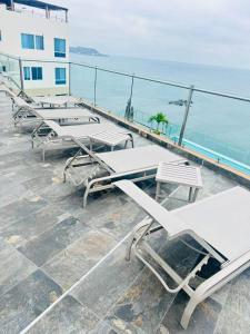 Una fila de mesas y sillas blancas en un edificio. en departamento salinas, en Salinas