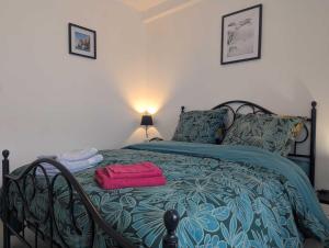 a bedroom with a bed with a green and blue blanket at Au petit café in Châteauvillain