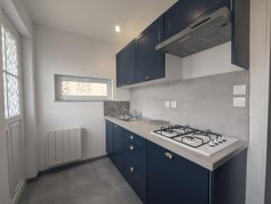 a kitchen with blue cabinets and a stove at Au petit café in Châteauvillain