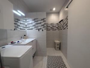 a white bathroom with a sink and a toilet at Au petit café in Châteauvillain