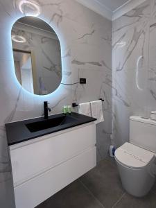 ein Badezimmer mit Waschbecken, Spiegel und Toilette in der Unterkunft Hume Villa Motor Inn UNDER NEW MANAGEMENT in Melbourne