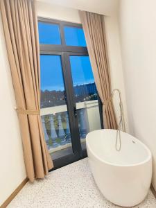 a bathroom with a bath tub in front of a window at Soffia Hotel in Phu Quoc