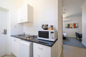 a white kitchen with a microwave and a stove at The Hallows Accommodation in Bathurst