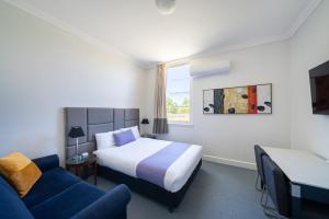 a hotel room with a bed and a blue couch at The Hallows Accommodation in Bathurst