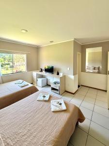 Una habitación de hotel con dos camas y una ventana. en Hotel Pousada Laguna Rosa, en Barra de Ibiraquera