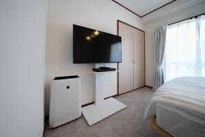 a bedroom with a bed and a flat screen tv on the wall at 3min walk to Asagaya Sta, Cozy Private Studio Direct access 8min to Shinjuku, 30min to Akihabara and Asakusa in Tokyo