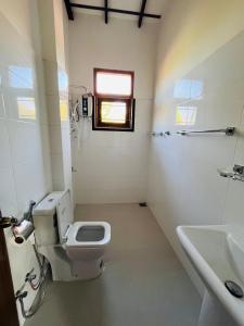 a bathroom with a toilet and a sink and a window at Anthony Guesthouse in Hikkaduwa