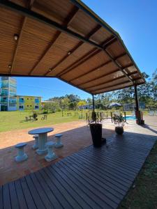 Un pabellón con una mesa de picnic y bancos en una terraza. en Hotel Pousada Laguna Rosa, en Barra de Ibiraquera