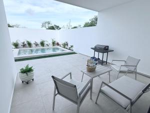 a patio with chairs and a table and a pool at Casa Honeybun in Mérida