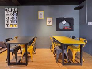 two tables and chairs in a restaurant with yellow chairs at East Home Stay in Dharmsala