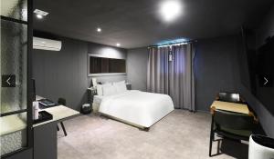 a bedroom with a large white bed and a desk at 월호텔 in Pyeongtaek +3 photos