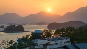 una puesta de sol sobre una ciudad y un río con montañas en Sacheon Bichae Pension, en Sacheon