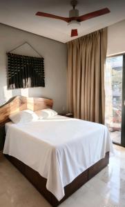 een slaapkamer met een wit bed met een plafondventilator bij The Empire Amira in Tulum