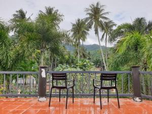 two chairs sitting on a porch with palm trees at Thai House by Dow Residence in Lamai