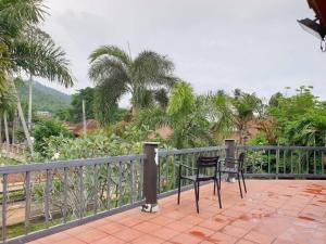 a balcony with two chairs and a fence and palm trees at Thai House by Dow Residence in Lamai