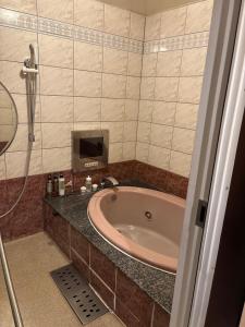 ein Badezimmer mit einer Badewanne und einem TV an der Wand in der Unterkunft ホテルエルリゾート in Koriyama + 3 Fotos
