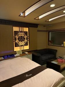 ein Schlafzimmer mit einem Bett, einem Stuhl und einem Bildschirm in der Unterkunft ホテルエルリゾート in Koriyama