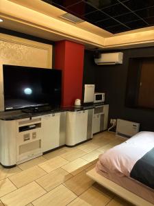 Schlafzimmer mit einem Flachbild-TV und einem Bett in der Unterkunft ホテルエルリゾート in Koriyama