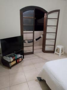 una camera con letto, TV e specchio di Casa Petrópolis a Petrópolis Altre 9 foto