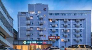 a tall blue building with cars parked in front of it at City Comfort Inn Liuzhou High-speed Railway Station in Liuzhou
