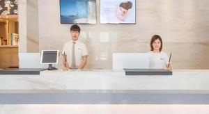 Ein Mann und eine Frau sitzen an einem Tresen in der Unterkunft City Comfort Inn Liuzhou Chengzhong Wanda Haiguan in Liuzhou