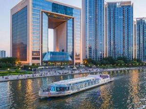 um barco em um rio em frente a uma cidade em Xana Hotelle Tianjin Binjiang Road Heping Road Metro Station Quanyechang em Tianjin