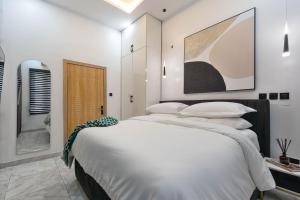 a white bedroom with a large bed with white pillows at Modern 3BR Smart Villa near Lekki Conservation with Inverter PS5, Hot Tub and Gym in Ibeju