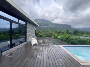 a house with a wooden deck with a swimming pool at Silvaate stay in Karjat