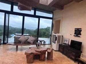 a living room with a table and a large window at Silvaate stay in Karjat