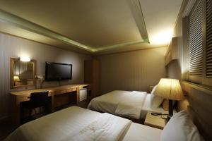 ソウルにあるホテル ノブレス イェオサムのベッド2台とテレビが備わるホテルルームです。