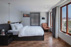 une chambre avec un lit, une chaise et des fenêtres dans l'établissement Monaco Hotel, à Sa Pa
