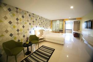 um quarto de hotel com uma cama, um sofá e cadeiras em Trebel Pattaya em Pattaya Central