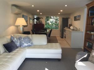 a living room with a white couch and a kitchen at Sunny Glen Cottage in Waikanae +7 photos