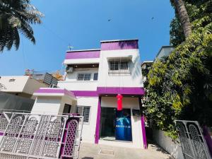 a white and purple house with a blue and red object at Hotel O Aundh Homtel in Dāpuri +5 photos