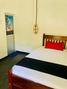 a bedroom with a bed with a red pillow at Relax point cabana & restaurant in Netolpitiya