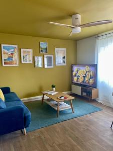 een woonkamer met een blauwe bank en een tv bij LE MOINET FAYARD in Vichy