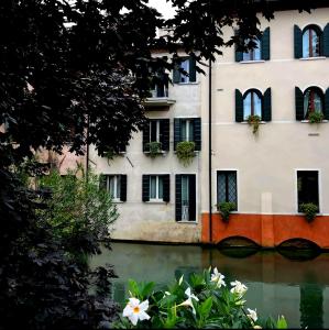un edificio con flores frente a un cuerpo de agua en B&B San Leonardo, en Treviso