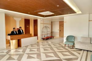 two people standing at a desk in a lobby at Hotel HPB Grand in Bhadohī
