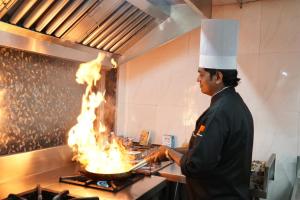 a chef cooking food on a grill with flames at Hotel HPB Grand in Bhadohī