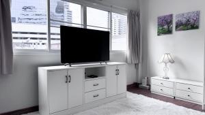 a living room with a flat screen tv on a white cabinet at Blissful Heaven Residence at BTS Phromphong Emdistrict Shopping Area in Bangkok