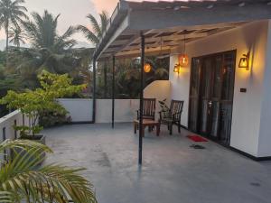 a porch of a house with two chairs and trees at Lake & Ocean Villa ahangama in Elagawagoda
