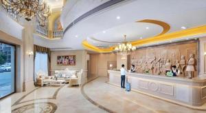 eine Person, die in einer Hotellobby steht und an deren Wand ein Gemälde hängt in der Unterkunft Vienna Hotel Anhui Guangde Development Zone in Guangde