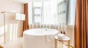 a white bathroom with a tub and a window at Vienna Hotel Shaanxi Xianyang Huitong China Square in Xianyang