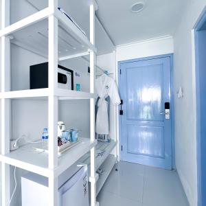 a white bathroom with a sink and a blue door at Jungwok Blue Ocean Resort in Ngandong