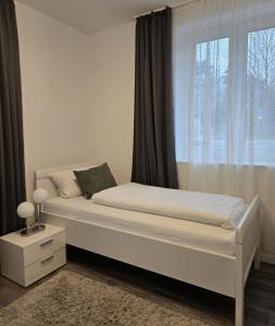 a white bed in a bedroom with a window at Schneider Apartments in Neustadt am Rübenberge