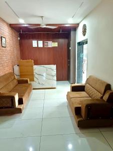 a living room with brown couches in a room at Hotel Skyline in Dholka +1 photo
